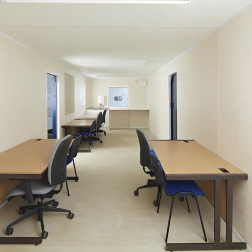 Interior view of a spacious office cabin featuring multiple desks and ergonomic chairs.